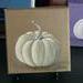 Photo of small square canvas painting of white pumpkin with a light brown background