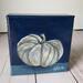 Photo of small square canvas painting of oddly shaped light blue pumpkin with a dark blue background