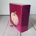 Photo of sideview of small square canvas painting of peach colored pumpkin with a raspberry pink background