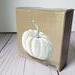 Photo of small square canvas painting of white pumpkin with a light brown background