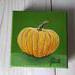 Photo of small square canvas painting of orange pumpkin with a olive green background
