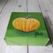 Photo of small square canvas painting of orange pumpkin with a olive green background