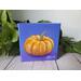 Photo of small square canvas painting of orange pumpkin with purple blue background