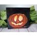 Photo of small square canvas painting of glowing jack o'lantern pumpkin with a black background