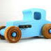 This handmade wooden toy car, modeled after a 1927 Ford T-Coupe, is hand-painted baby blue with black and metallic sapphire blue. The wheels are finished with nonmarring amber shellac.