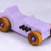 This toy is a beautifully crafted wooden toy car in a '27 T-Bucket Hot Rod style. The car has been painted with a high gloss lavender finish and features black acrylic paint trim. The wheels are non-marring and have an amber shellac finish.