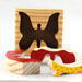 A wooden three-piece butterfly tray puzzle, handmade and finished. The butterfly is painted bright red and yellow with orange spots. The wooden tray is finished with clear shellac. It is one of four puzzles in my Puzzle Pals Collection.
