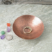 photo showing hand hammered copper trinket bowl 3 inch diameter with ring and dime for size comparison