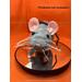 A gray rat plushie stands on a mirror pedestal, facing the camera. Text reads: Pedestal not included.