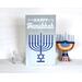Happy Hanukkah Sign, Menorah With Jewish Star Of David

Celebrate the miracle of lights with this traditional Happy Hanukkah sign. This will make a beautiful addition to your Jewish holiday decor with its gray and blue ombre background and bright blue lit menorah displaying the star of David. Give this unique sign as a gift or keep it or yourself to pass down for generations to come. This sign comes ready to hang and can also stand alone on a shelf or mantel.