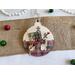 ornament with gingerbread background, includes buttons, cranberry pips, a stamp, mini ticket strip, and a mini ornament tag.