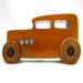 This handmade wooden toy car is based on a 1932 Ford Sedan Hot Rod. It is hand-finished with multiple coats of amber shellac and trimmed with black and grey acrylic paint.