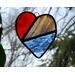 Stained glass heart in red, white, and blue with nature in the background