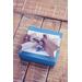 Turquoise blue gift box with gift tag and silver ribbon on neutral wood background. 