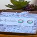 Small silver round stud earrings featuring turquoise blue waves and peach colored sand. On white earring card with Fresh Air Designs Photo.