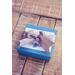 Sample gift packaging with blue gift box, gift tag and silver ribbon featured on wooden background.