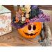 This image shows a fall table Halloween centerpiece. It is a witch made from a real gourd. Her name is Violet and has a purple witch hat.