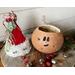 This image shows the Christmas elf hat sitting next to the carved elf gourd. Red and silver jingle bells lay next to the gourd display.