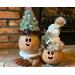 This is a picture of two Christmas gourd decorations. They are made to look like elves with happy faces carved into the gourd shells. 