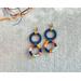 Colorful threads wrapped tightly around two circles give these fun earrings a tropical vibe.
2 x 7/8 in, 
gold plated ball post and backing