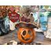 This is a fall gourd carved to look like a pumpkin. It has a handmade burlap hat decorated with fall leaves and berries. 