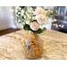 A handmade sunflower vase,  filled with faux daisies and zinnias, decorates a kitchen island. The vase is made from a dried gourd. 