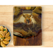 A handcrafted serving board made from salvaged teak with cutout handle. Rich, warm resin artwork with a highland cow and ribbons of 24K gold
