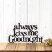 Always Kiss Me Goodnight metal wall art, in matte black powder coat. Placed against a white wood wall.