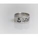 sterling silver ring with an anchor an the word til on it in black