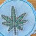 3" round light blue denim patch with a green embroidered marijauna leaf in the center.