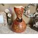 This is a handmade gourd vase with hummingbird artwork. The rim is carved with a wavy edge. The vase decorates and entryway table. 
