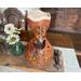 This show handmade gourd vase decorating a dining table. It features hand drawn hummingbird enjoying garden flowers swirling around it.  