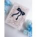 Black loose flowy bow shaped table place card with handwritten name using white calligraphy ink used as a gift tag