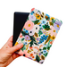 A hand holding a beautiful, floral padded pouch that holds a Kindle e-reader.  The padded sleeve is made with Rifle Paper co floral fabric.