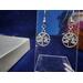 Round dangle earrings with a rhinestone encrusted leaf pattern in the center on stainless steel fish hook ear wires.