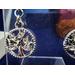 Detail of round dangle that has a rhinestone encrusted leaf pattern in the center.