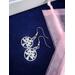 Round dangle earrings with a rhinestone encrusted leaf pattern in the center on stainless steel fish hook ear wires.