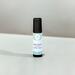 Best Man essential oil roller bottle on a matte white surface against a white wall with a subtle shadow where they meet.