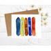 Greeting card with watercolor snowboards of yellow, blue, brown orange.