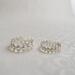 Two sterling silver daisy rings, 3mm and 4mm wide, with embossed floral designs, on a white textured surface.

