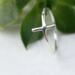 Sleek sterling silver sideways cross ring on white background.
