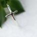 Sleek sterling silver sideways cross ring on white background.
