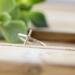 Sleek sterling silver sideways cross ring on wood background.

