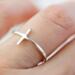 Chic sterling silver sideways cross ring on finger, perfect for daily wear with a playful faith twist.
