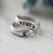  Two sterling silver rings with "SAMI" and paw prints on a white surface. 
