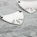 Handcrafted sterling silver fern-stamped hoop earrings on a wooden surface, showcasing elegant leaf designs. 
