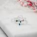 Four dainty sterling silver stacking rings with green, blue, and pink cubic zirconia birthstones, displayed on a white marble surface.
