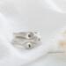  Three sterling silver stackable rings with lowercase initials "a," heart, and "t" on a white  background with dried flowers
