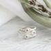 Three sterling silver stackable rings with lowercase initials "a," heart, and "t" on a white  background with dried flowers
