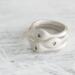  Three sterling silver stackable rings with lowercase initials "a," heart, and "t" on a white  background with dried flowers

